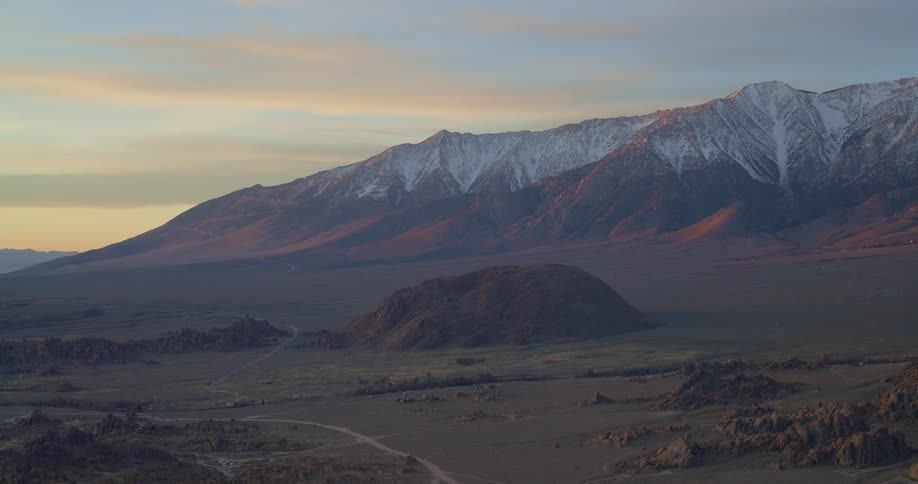 Mound and rock formations on the side of a rural road with mountains across the landscape