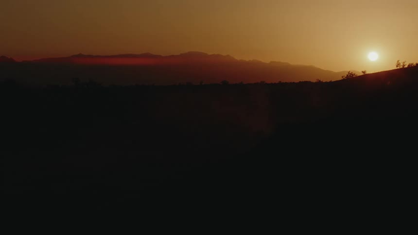 The sun is rising over the dark mountains