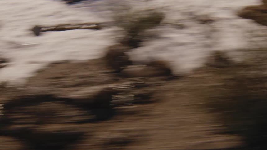 Mountain slope with trees and patches of snow in horizontal motion blur