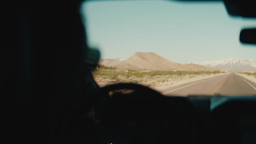 A person driving a car on a road surrounded by mountains