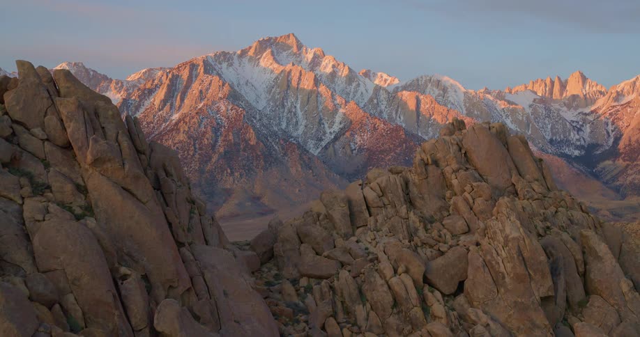 A wide vast stretch of land filled with mountain ranges in the wilderness at sunrise