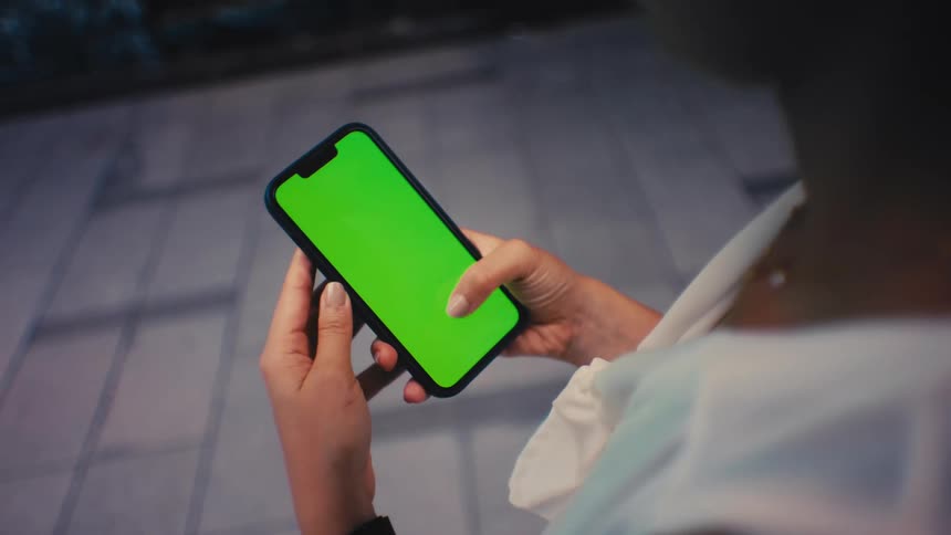 Person holding smartphone with both hands above tiled floor