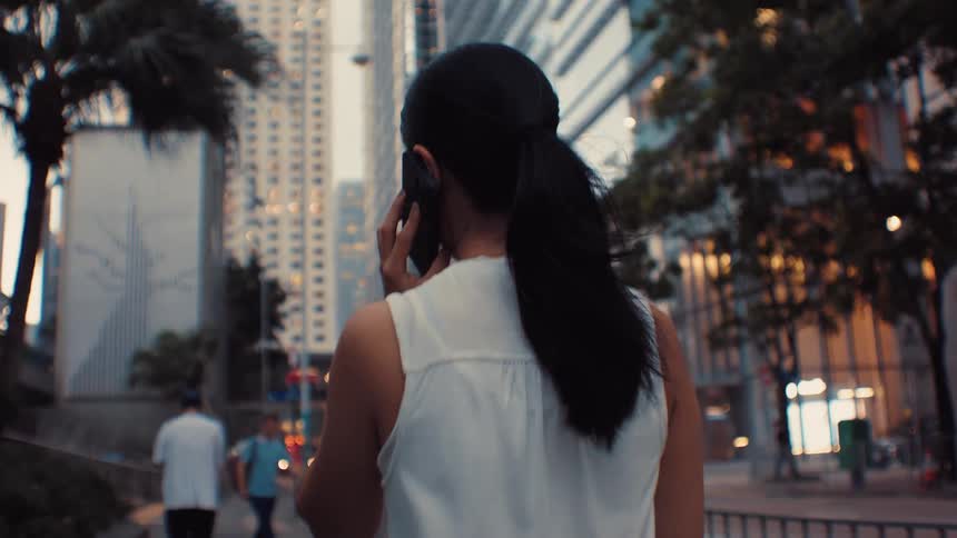 Young woman walking downtown talking on her smart phone