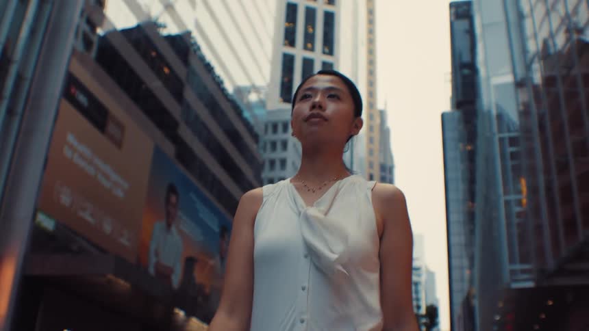 Woman wearing a white blouse standing between skyscrapers in an urban setting
