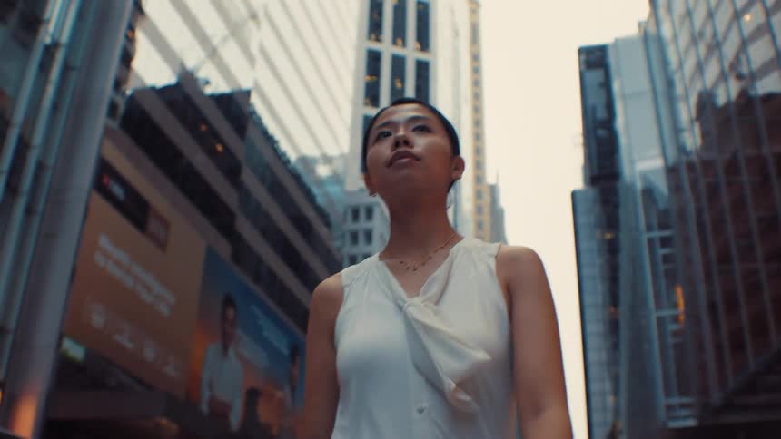 Woman wearing a white blouse standing between skyscrapers in an urban setting