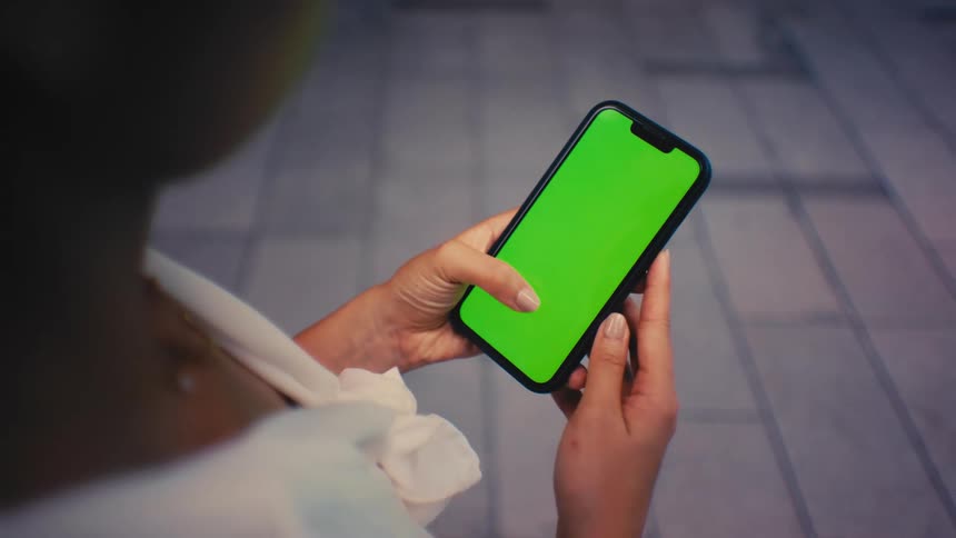 Young woman holds her phone with both hands and moves her thumb across the screen