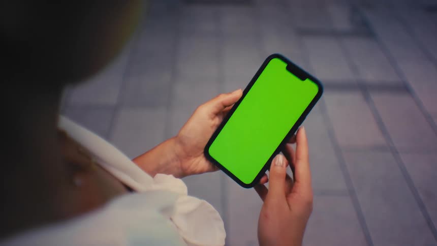 Young woman holds her phone with both hands and moves her thumb across the screen