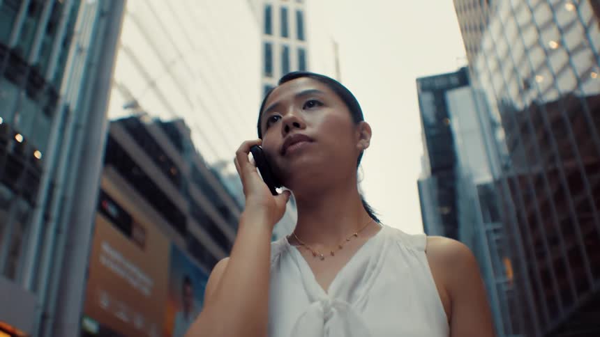 Young woman walking downtown talking on her smart phone