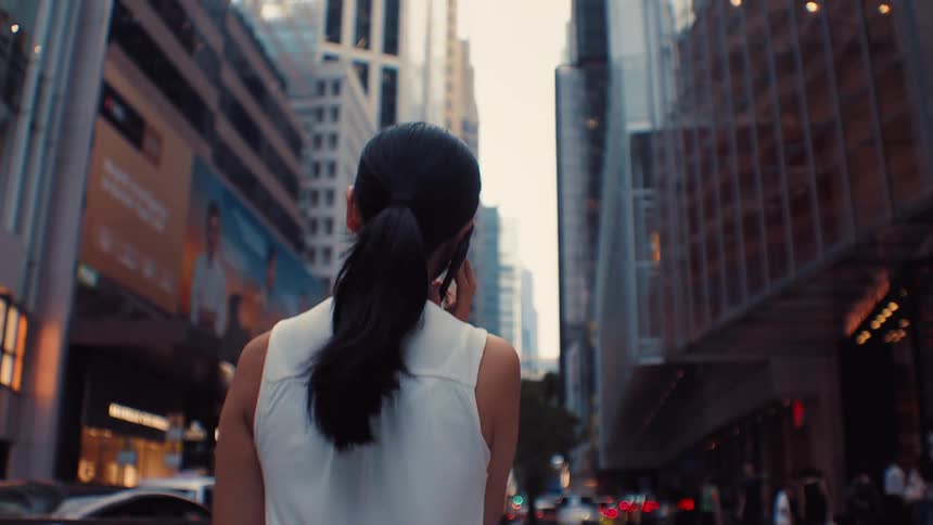 Woman with tied hair talking on phone in busy city street