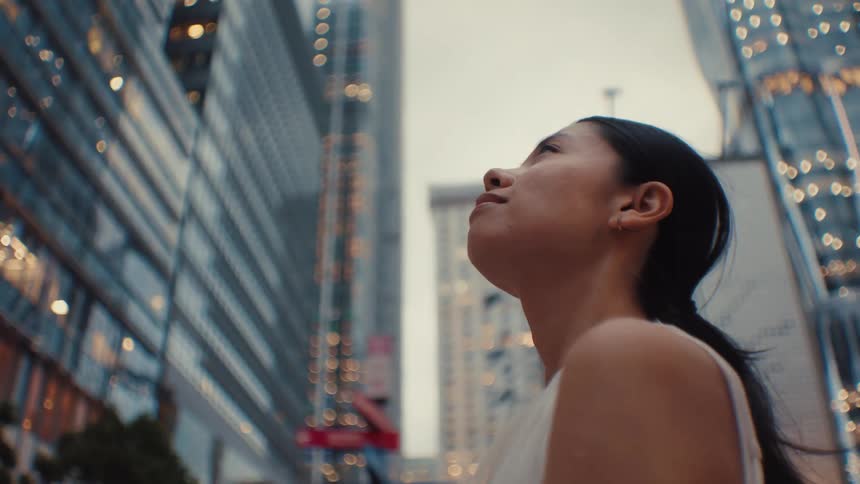 The woman smiles while looking around the city