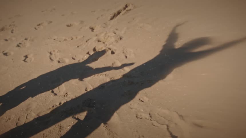 Shadows of a woman and her child playing on the beach