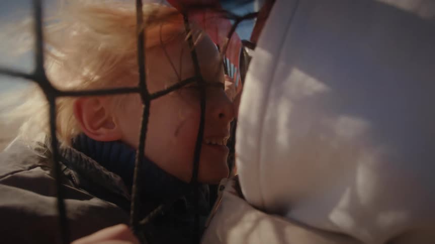The mother kisses her son through the volleyball net