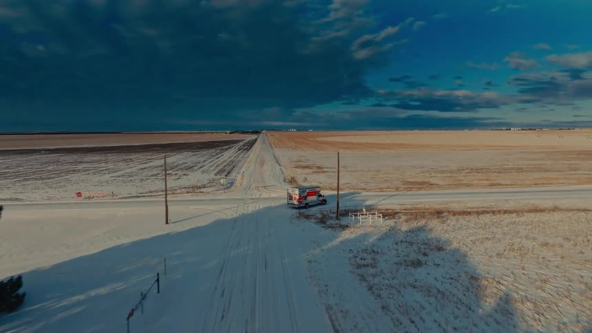 Uhaul truck stopped at a snowcovered rural intersection surrounded by fields
