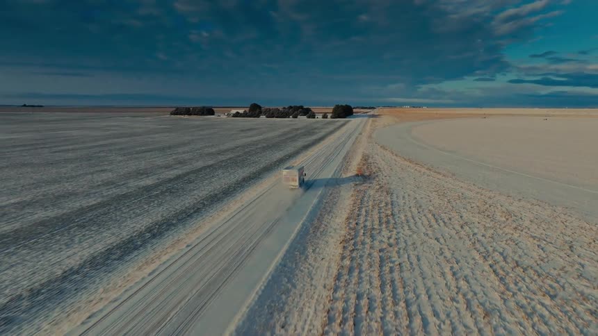 Uhaul truck driving on a snowcovered rural road between open fields