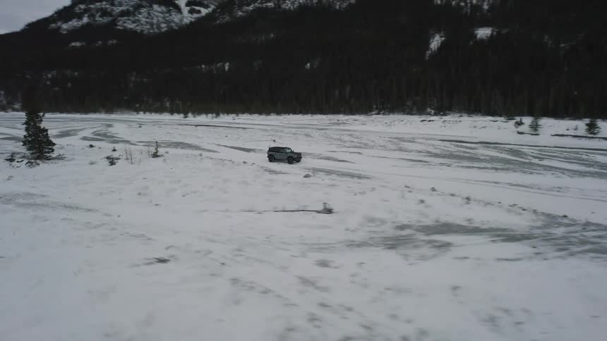 A sport utility vehicle drives across a snow covered landscape