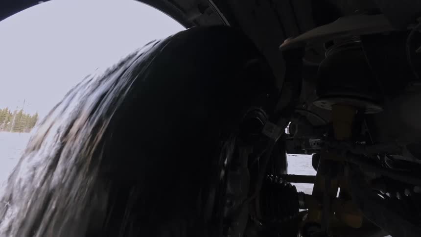 Ice particles fly from the wheel of a vehicle travelling through the snow on a winter day
