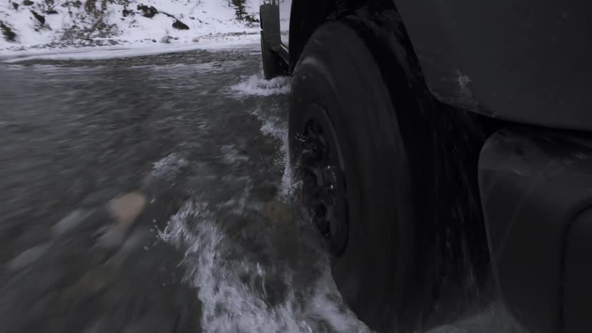Vehicle wheel crossing a section with water and snow on the road
