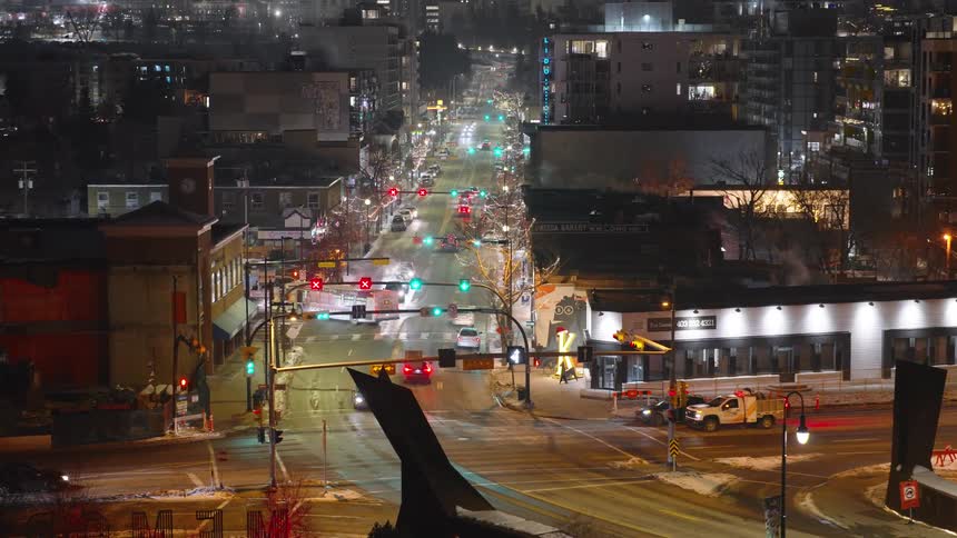 Urban avenue at night with vehicle traffic and illuminated traffic lights