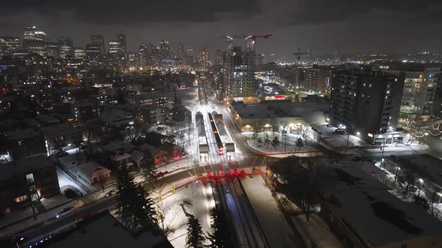 Aerial nighttime view of city with illuminated train tracks and surrounding buildings