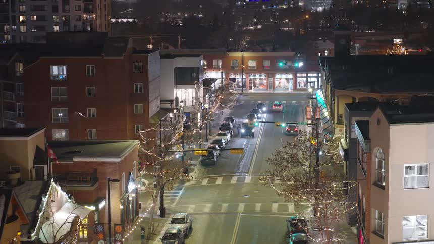 Urban intersection at night with illuminated buildings vehicles and decorative lights on the trees