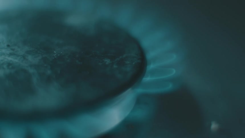 Blue flames come out of a gas fueled burner on a black stovetop
