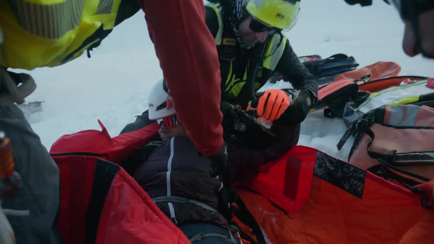 A group of rescuers work together to aid a climber in an snowy environment