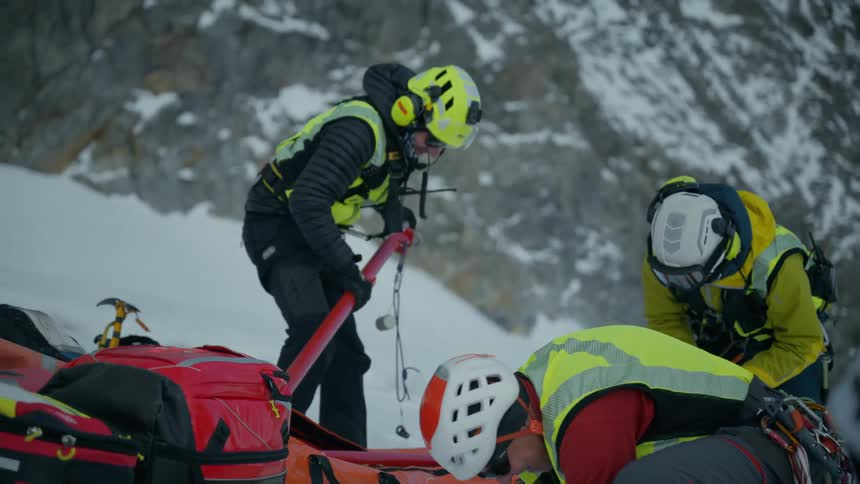 Mountain rescue workers prepare equipment and a stretcher on snowy slopes