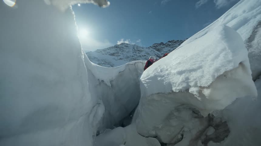 Mountaineer descending into a deep glacier crevasse surrounded by large ice formations