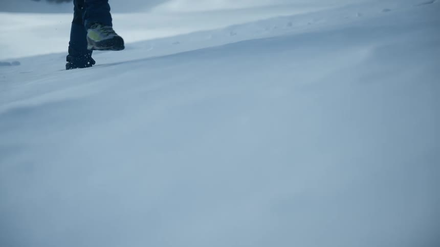 Man walking on a snow covered mountain with a rope on his belt