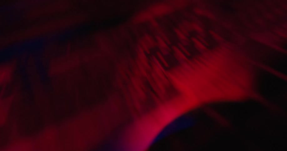 A close view shows dark textures and geometric patterns moving rapidly under a deep red light in a technical environment