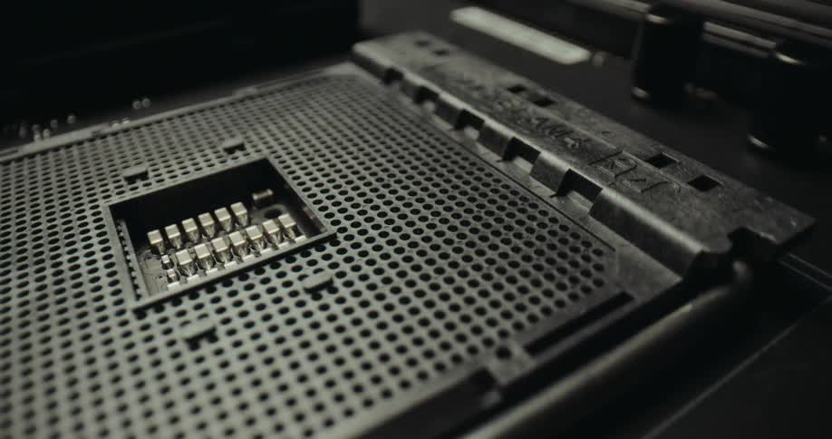 A close view shows an empty black computer processor socket with many small pins on a motherboard in a dark technical setting