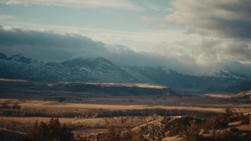 Wide valley landscape with mountains in the background under a partly cloudy sky
