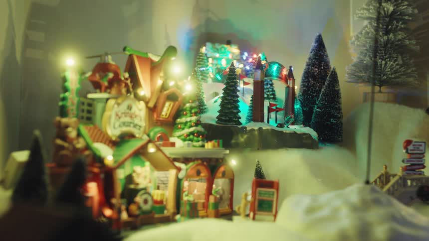 A miniature christmas village display with glowing lights and flying sleigh