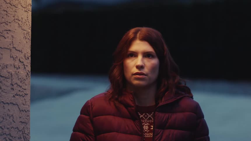 Woman wearing a padded jacket stands outdoors at night
