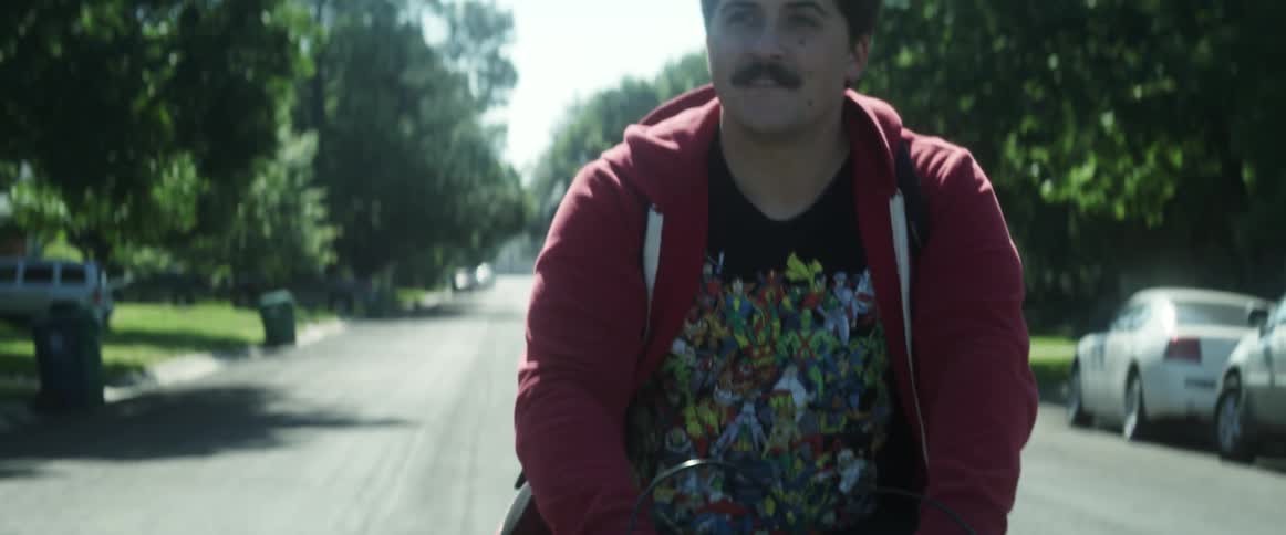 A man rides a bicycle down the middle of a neighborhood street during the day