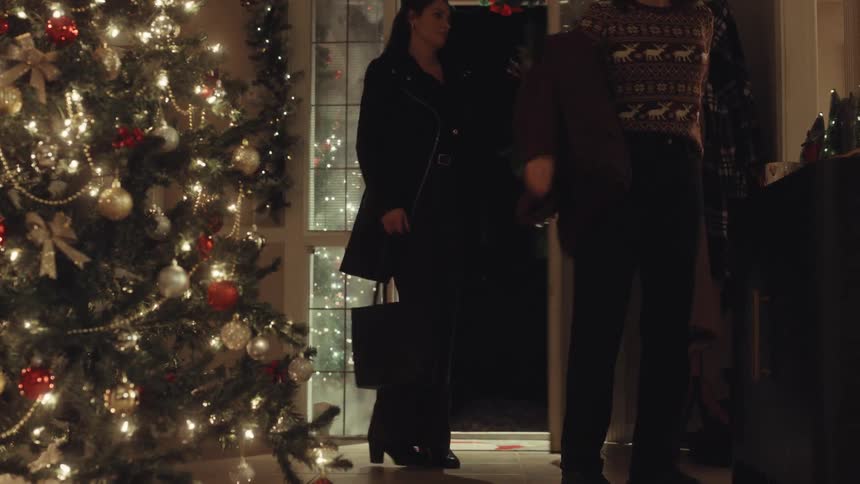Person enters a house decorated with a lit christmas tree