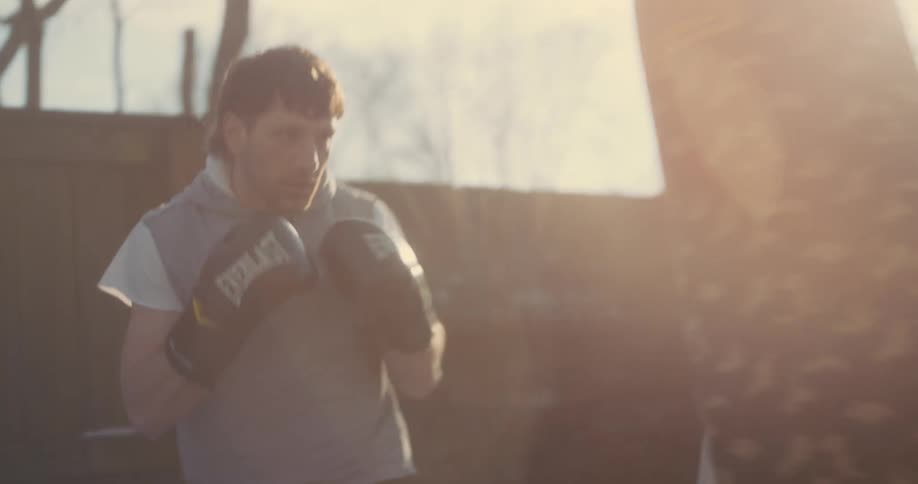 Fighter trains with camouflage punching bag outdoors