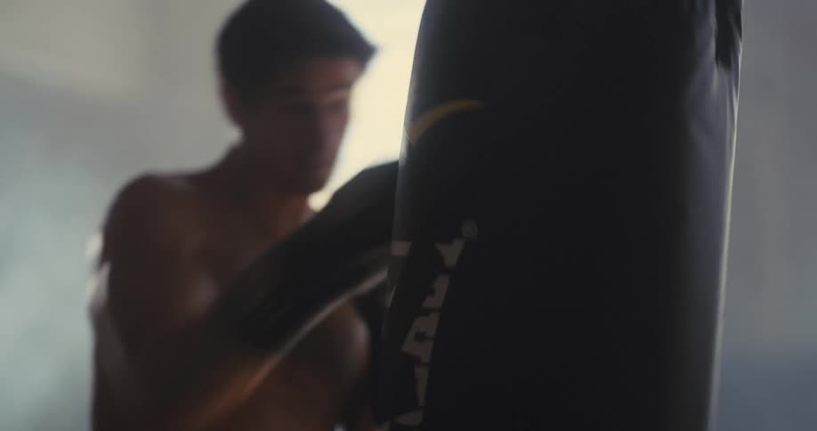 Man trains punches on a punching bag indoors