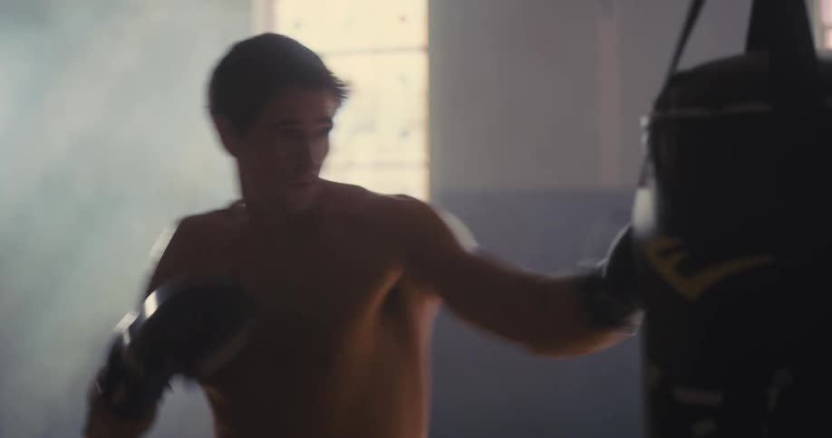 Man practices boxing punches on a punching bag indoors