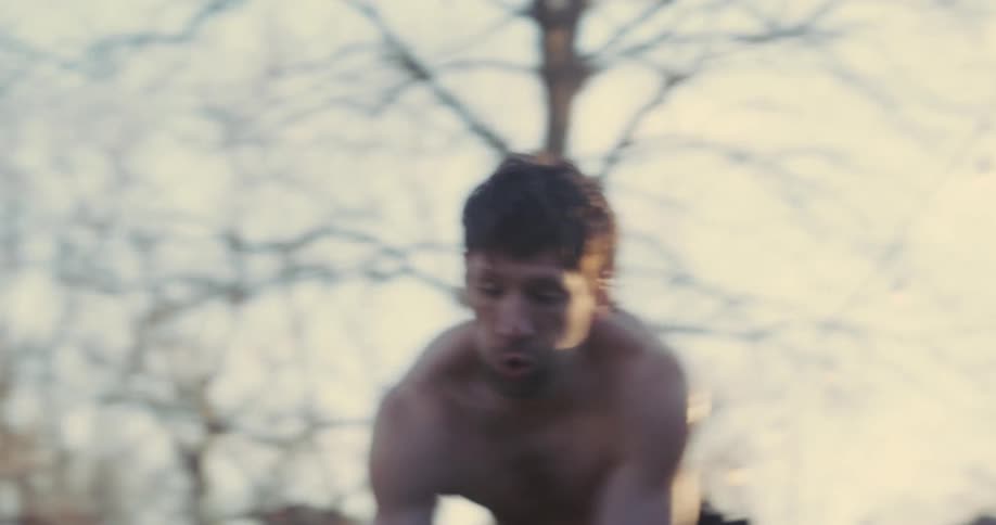 Shirtless man exercises by hitting a tire with a sledgehammer on a winter day