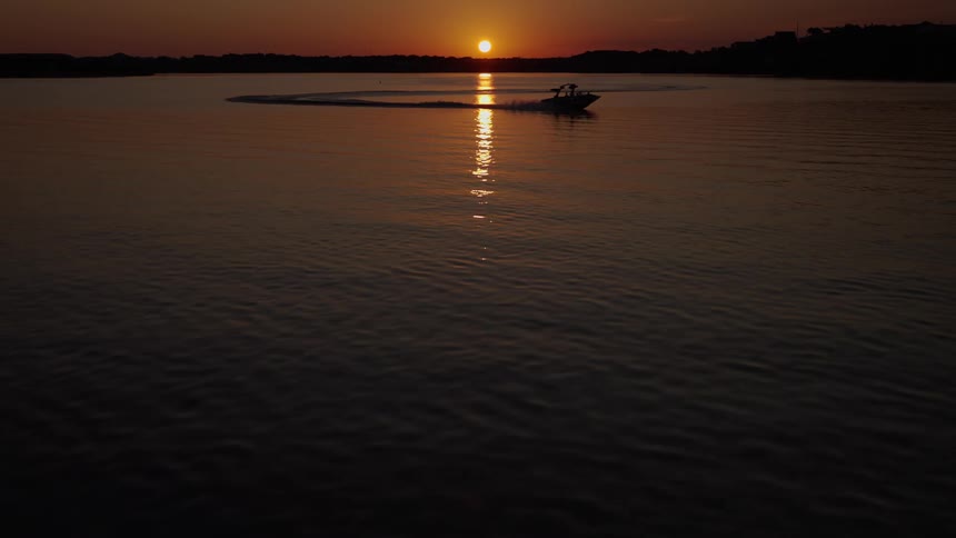 Small boat sailing off the coast as the setting sun reflects on the water