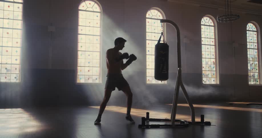 The man is punching the heavy bag in the hall