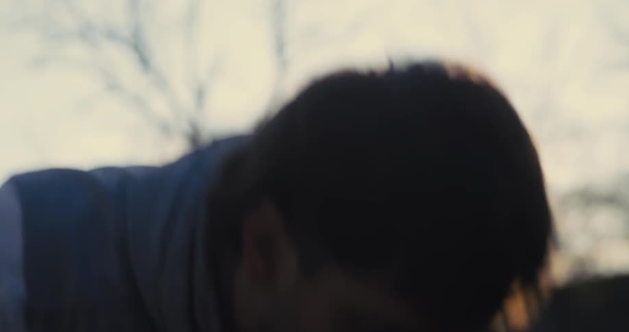 Man performs a pushup outdoors under golden sunset light