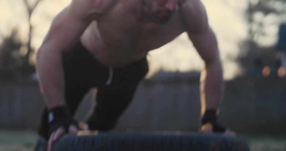 Athlete performs pushup on tire outdoors