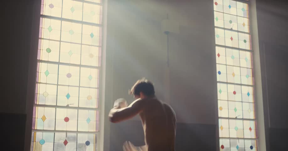 Man practices boxing movements in front of stained glass windows