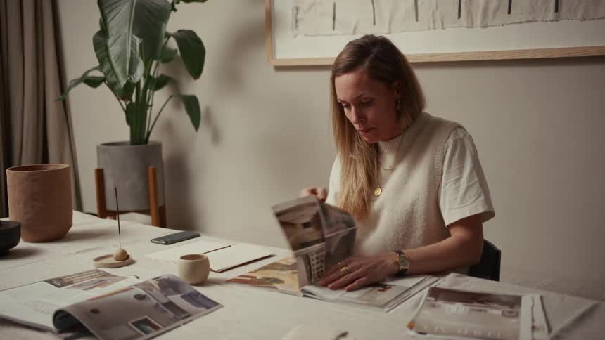 Person reads magazines while drinking from white cup