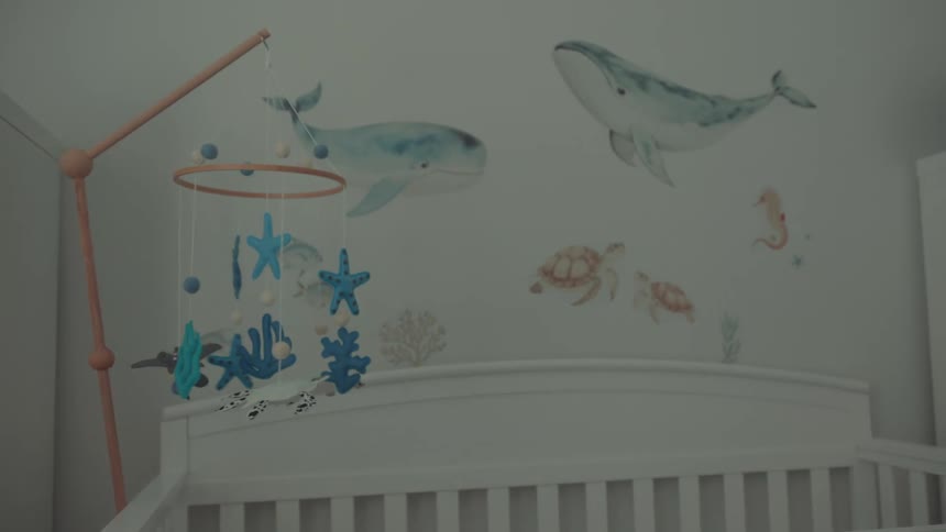 Nursery decorated with ocean theme and mobile of sea creatures above crib