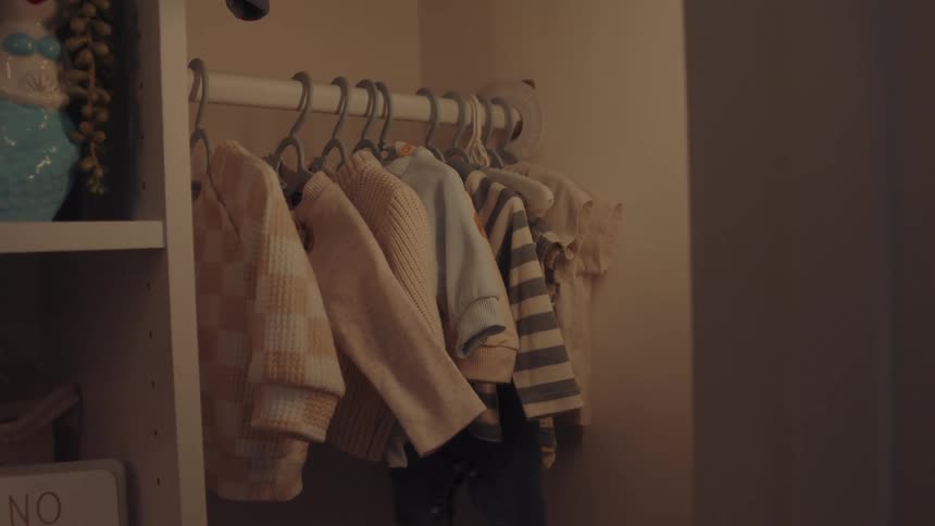 A wardrobe with a series of knitwear hanging on hangers alongside other casual clothing