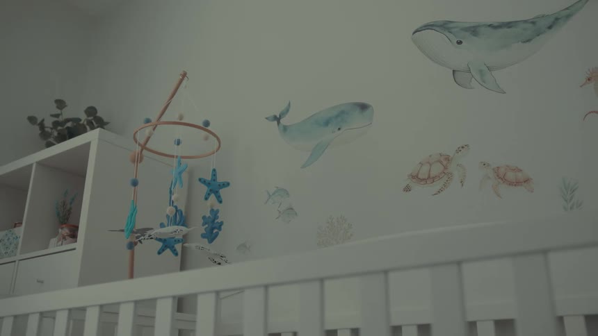 Baby mobile and pictures drawn on the wall demonstrate a sea life theme for a babys room