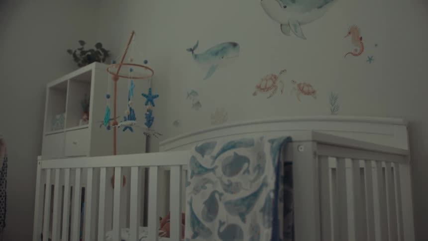 A baby crib with a whale blanket in a nautical themed nursery room